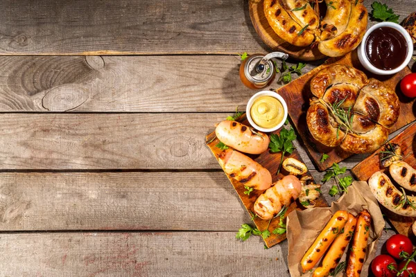 Bavyera sosisi, yuvarlak, gumberland, ketçaplı sucuk, hardal barbekü sosu. Çeşitli bbq ızgara sosisler ahşap arka planda yatıyordu. Sokak festivali ızgara yemek menüsü. 