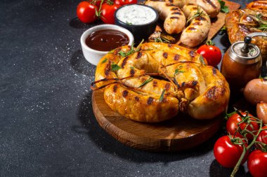 Bavyera sosisi, yuvarlak, gumberland, ketçaplı sucuk, hardal barbekü sosu. Çeşitli bbq ızgara sosisler siyah arka planda yatıyordu. Sokak festivali ızgara yemek menüsü