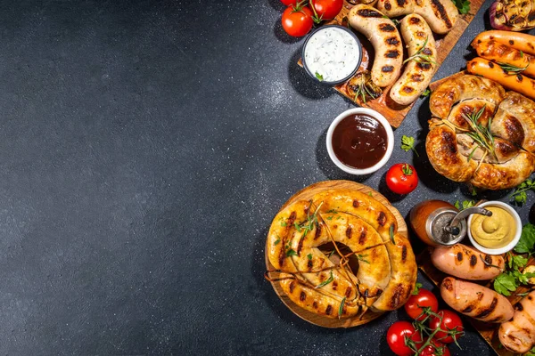 Bavyera sosisi, yuvarlak, gumberland, ketçaplı sucuk, hardal barbekü sosu. Çeşitli bbq ızgara sosisler siyah arka planda yatıyordu. Sokak festivali ızgara yemek menüsü