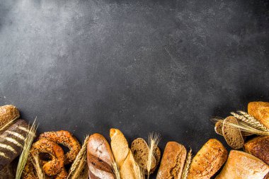 Çeşit çeşit lezzetli taze pişmiş ekmek, siyah beton arka plan üst görünüm kopya alanı