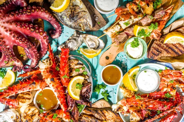 Çeşitli barbekü çeşitleri Akdeniz ızgara gıdaları - balık, ahtapot, karides, yengeç, deniz ürünleri, midye, yaz diyeti bbq parti festivali, kebap, soslar, açık mavi sunne ahşap arka plan