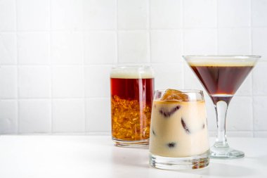 Beyaz arka planda çeşitli kokteyl bardaklarında üç kahve içeceği seti.