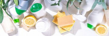 Çevre dostu organik temizlik konsepti. Çevre dostu temizlik aletleri - eko fırçalar, aletler süngerler, doğal temizlik ürünleri, soda, sabun, limon, sirke, beyaz arka planda yeşil yapraklı şişeler