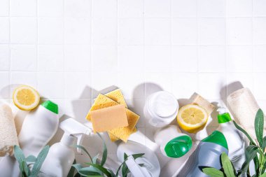 Çevre dostu organik temizlik konsepti. Çevre dostu temizlik aletleri - eko fırçalar, aletler süngerler, doğal temizlik ürünleri, soda, sabun, limon, sirke, beyaz arka planda yeşil yapraklı şişeler