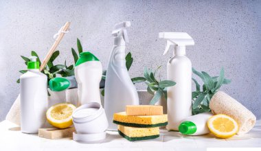 Çevre dostu organik temizlik konsepti. Çevre dostu temizlik aletleri - eko fırçalar, aletler süngerler, doğal temizlik ürünleri, soda, sabun, limon, sirke, beyaz arka planda yeşil yapraklı şişeler