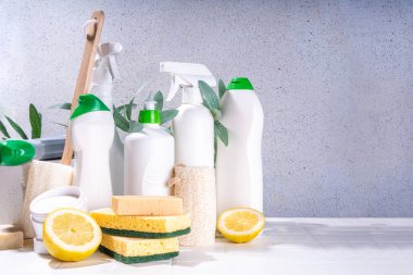 Çevre dostu organik temizlik konsepti. Çevre dostu temizlik aletleri - eko fırçalar, aletler süngerler, doğal temizlik ürünleri, soda, sabun, limon, sirke, beyaz arka planda yeşil yapraklı şişeler