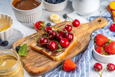  Amerikan Avrupa yaz kahvaltısı sandviçleri, fıstık ezmeli tostlar, çikolata ve krem peynirli böğürtlen ve meyveli krem peynir, mutfak masasının üstünde düz tabaka.