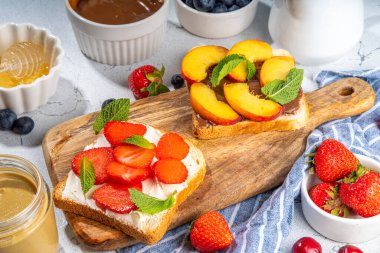  Amerikan Avrupa yaz kahvaltısı sandviçleri, fıstık ezmeli tostlar, çikolata ve krem peynirli böğürtlen ve meyveli krem peynir, mutfak masasının üstünde düz tabaka.