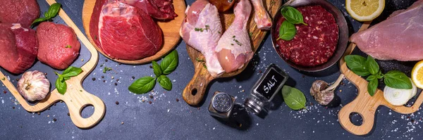 Various meat cooking background. Variety of red and white meat, patty, heart, liver, with spices and ingredients for cooking.