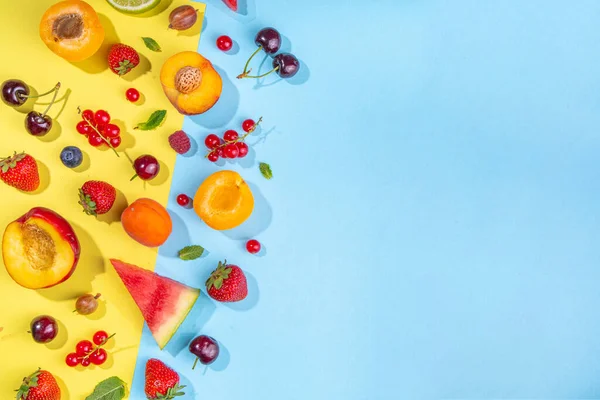 Summer vitamin food concept, various fruit and berries watermelon peach mint plum apricots blueberry strawberry currant, creative flat lay on yellow background top view copy space