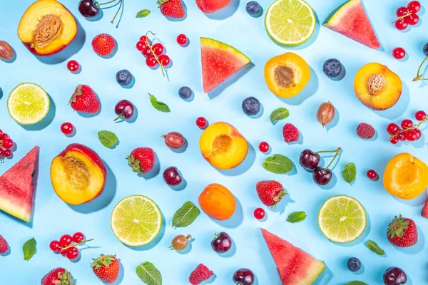 Summer vitamin food concept, various fruit and berries watermelon peach mint plum apricots blueberry strawberry currant, creative flat lay on light blue background top view copy space