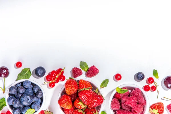 Summer vitamin food concept, set of various berries blueberry strawberry currant,  flat lay on white background top view copy space