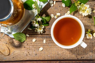 Bitkisel yasemin çiçeği çayı. Cam çaydanlıkta yasemin yeşili çay ve taze yasemin çiçekli beyaz çay fincanı.