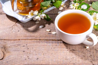 Bitkisel yasemin çiçeği çayı. Cam çaydanlıkta yasemin yeşili çay ve taze yasemin çiçekli beyaz çay fincanı.