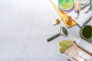Doğa Yaşlanma Karşıtı Kozmetik, Terapi Masajı. Asya güzellik bakımı. Yeşim silindir, gua sha masaj aleti çeşitli organik serumlar, jel, bitkisel özler, spa havluları. Beyaz mermer arka planda düz alan