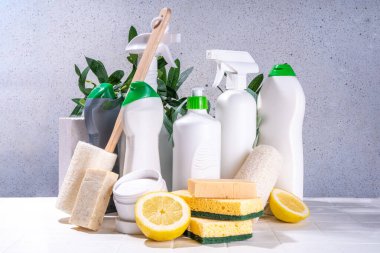 Çevre dostu organik temizlik konsepti. Çevre dostu temizlik aletleri - eko fırçalar, aletler süngerler, doğal temizlik ürünleri, soda, sabun, limon, sirke, beyaz arka planda yeşil yapraklı şişeler