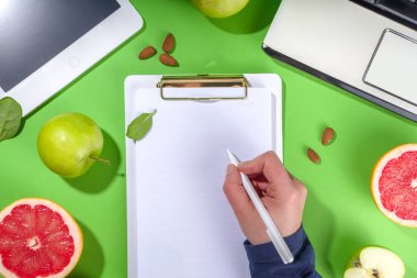 Yemek diyet planı konsepti, not defterinde, sağlıklı yiyecek meyveleri, sebzeler, tablet, not defterleri ve parlak yeşil masa arkaplanını sümüklendirmek için aksesuarlar ile