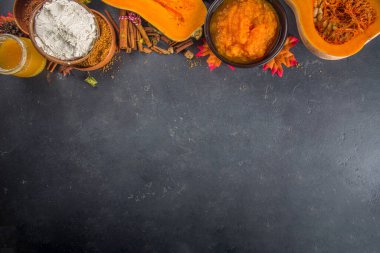 Sonbahar geleneksel pişirme arka planı. Balkabağı turtası, balkabağı baharatı, yarım dilimlenmiş balkabağı, un, kap kacak ve sonbahar dekorasyonu için malzemeler, üst görünüm kopya alanı