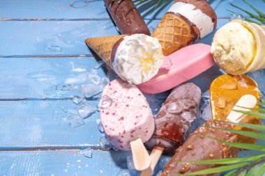 Siyah arka planda çeşitli dondurma setleri. Tahta mavi plaj zemininde buzlu dondurma ve koni çeşitleri ve tropikal palmiye yaprakları üst düz görünüm kopya alanı