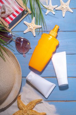 Güneş kremi geçmişi. Tatil aksesuarı, güneş losyonu şişesi, kozmetik krem, deniz kabukları, saman kadın şapkası güneş gözlüğü, üst görünüm kopya alanı.