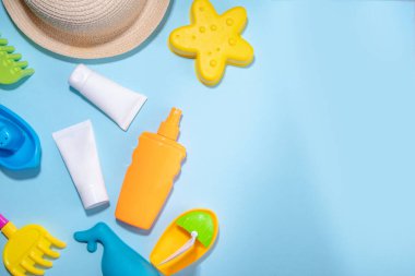 Bebek güneş kremi konsepti. Çocuklarla birlikte güneş kremi şişeleri tatil aksesuarları, kum kalıpları, panama şapkaları, açık mavi arka plan fotokopi alanı.