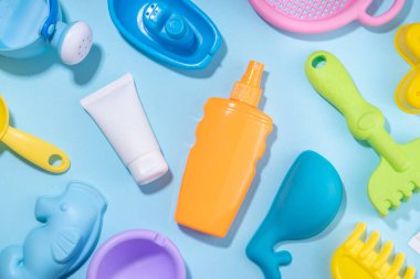 Bebek güneş kremi konsepti. Çocuklarla birlikte güneş kremi şişeleri tatil aksesuarları, kum kalıpları, panama şapkaları, açık mavi arka plan fotokopi alanı.