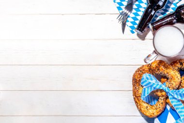Oktoberfest tatil geçmişi, menü modeli. Bavyera bayrağı Oktoberfest festivali peçetesi, pretzel, bira şişesi ve kupası beyaz ahşap arka planda.
