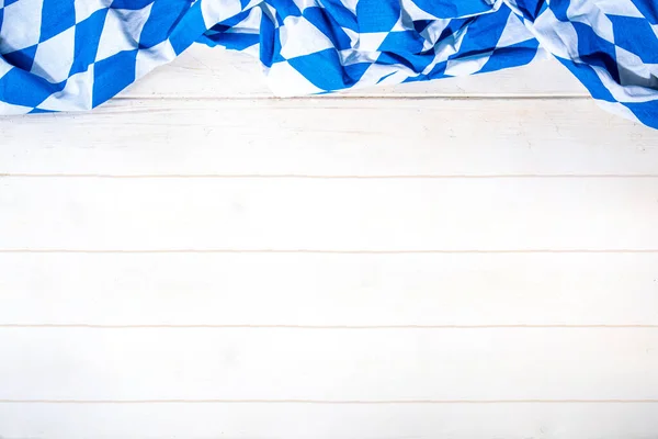 Oktoberfest holiday background, menu mockup. Bavaria flag oktoberfest festival napkin, pretzel, beer bottle and mug on white wooden background, copy space top view