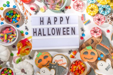 Beyaz arka planda çeşitli klasik Cadılar Bayramı ödülleri. Geleneksel kurabiyeler, zencefilli kurabiye, şeker, şeker ve balkabağı. Şaka mı şeker mi konsepti, üst görünüm kopyalama alanı