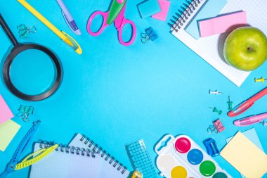 Düz bir zemin, parlak mavi arka planda renkli eğitim malzemeleri vardı. Okul konseptine geri dönelim. Okul çantasında makas, not defteri, kalem, kalem ve malzeme var. Üst görünüm, üstten kopyalama alanı