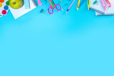 Düz bir zemin, parlak mavi arka planda renkli eğitim malzemeleri vardı. Okul konseptine geri dönelim. Okul çantasında makas, not defteri, kalem, kalem ve malzeme var. Üst görünüm, üstten kopyalama alanı