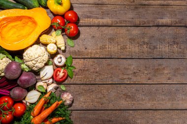 Sonbahar sebzeleri pişirme arka planı. Organik sonbahar hasat çiftliği sebzeleri, mantarlar. Ahşap mutfak arka planında akşam yemeği hazırlamak için çeşitli vejetaryen malzemeler.