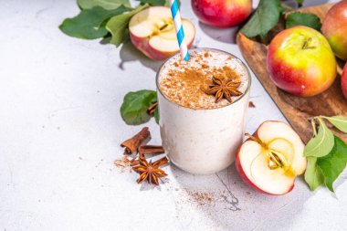 Apple pie smoothie with yogurt, apple slices, oatmeal granola flakes, cinnamon, spices and walnuts. Healthy uatumn breakfast or snack, with fresh raw apples and spices copy space