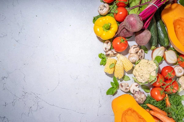 Autumn vegetables cooking background. Organic fall harvest farm vegetables, mushrooms. Various vegetarian ingredients set for cooking dinner on white kitchen background, top view copy space