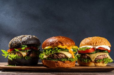 Lezzetli ev yapımı burger. Lezzetli çizburger, biftek ve jambon, taze sebze, ağız sulandıran lezzetli sos, koyu ahşap arka plan fotokopi alanı.