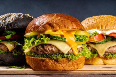 Lezzetli ev yapımı burger. Lezzetli çizburger, biftek ve jambon, taze sebze, ağız sulandıran lezzetli sos, koyu ahşap arka plan fotokopi alanı.