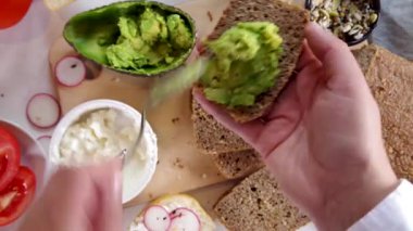 Sağlıklı beslenme atıştırmalıkları için sandviç yapıyorum. Avokado, krem peynir ve taze sebzeli çavdar ve chiabatta ekmeği.