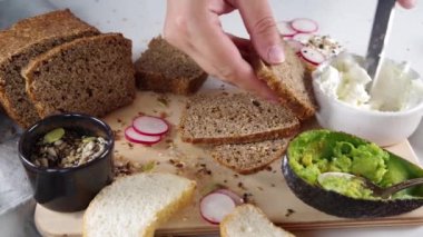Sağlıklı beslenme atıştırmalıkları için sandviç yapıyorum. Avokado, krem peynir ve taze sebzeli çavdar ve chiabatta ekmeği.