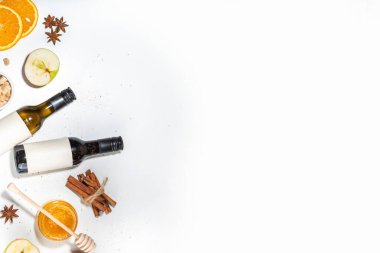 Beyaz zemin üzerine kurulmuş farklı şarap malzemeleri, şarap şişesi, tarçın, elma, portakal, anason yıldızı, basit sonbahar içeceği yemek pişirme arka planı.