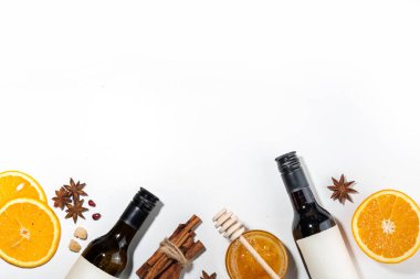 Beyaz zemin üzerine kurulmuş farklı şarap malzemeleri, şarap şişesi, tarçın, elma, portakal, anason yıldızı, basit sonbahar içeceği yemek pişirme arka planı.