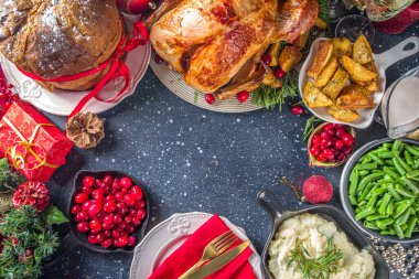 Noel ya da yeni yıl hindi yemeği. Fırında hindi, patates, kırmızı böğürtlen ve adaçayı, Noel yemeği masasında Noel ağacı, hediye ve mum.