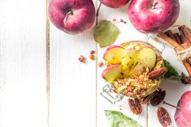 Sonbahar elmalı cevizli yulaf ezmesi, kırmızı elmalı yulaf lapası, cevizli fındık ve karamel sosu, beyaz ahşap arka plan fotokopi alanı.