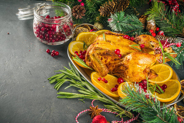 Traditional homemade Christmas chicken. Oven baked chicken with orange, cranberry rosemary and spices, over dark stone background copy space