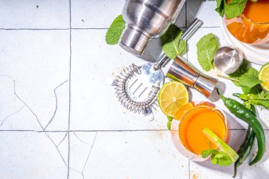  Carrot Ginger Margarita cocktail with lime, mint and hot chili pepper, original vegetable spicy drink on white tiled background copy space