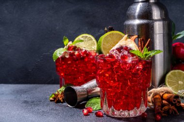 Spicy autumn pomegranate cocktail. Alcohol warming gin drink with pomegranate, lime, cinnamon, mint, autumn winter sangria on dark background copy space
