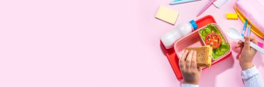 Healthy school meal, back to school concept. Children packed lunch box with balanced diet snack food - yogurt, cereal toast sandwich, apple, fresh vegetable salad, high-colored bright background