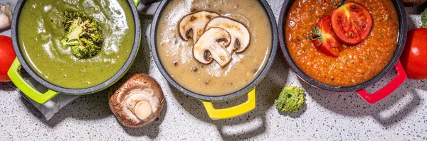 Autumn vegetable cream soups set. Three portion pots with various vegan hot vegetable cream soups tomato, mushrooms, broccoli on rustic wooden table copy space