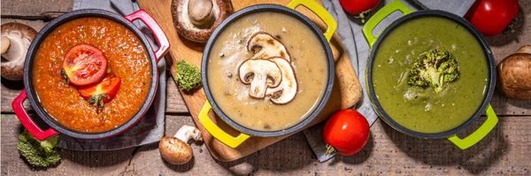 Autumn vegetable cream soups set. Three portion pots with various vegan hot vegetable cream soups tomato, mushrooms, broccoli on rustic wooden table copy space