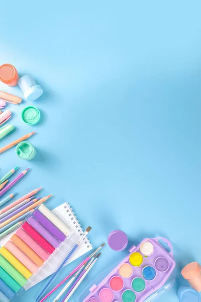 Online study and drawing, distantly painting class. Various colorful stationery and supplies for drawing. paints, pastels, pencils, brushes, tablet on blue background. Flatlay top view  copy space