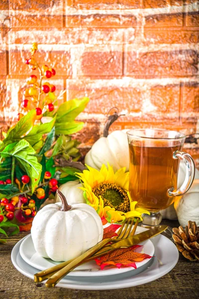 Thanksgiving Food concept. Autumn Table Setting with Plate, Tea cup, pumpkins, Sunflower and Warm Plaid or Sweater, comfort and cozy brick wood home background copy space